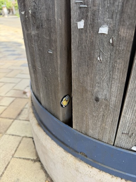 A duck tag tucked into the gap of a wooden barrel planter