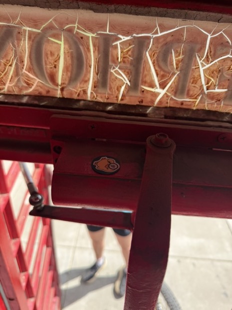 A duck tag on the frame of an old red trolley